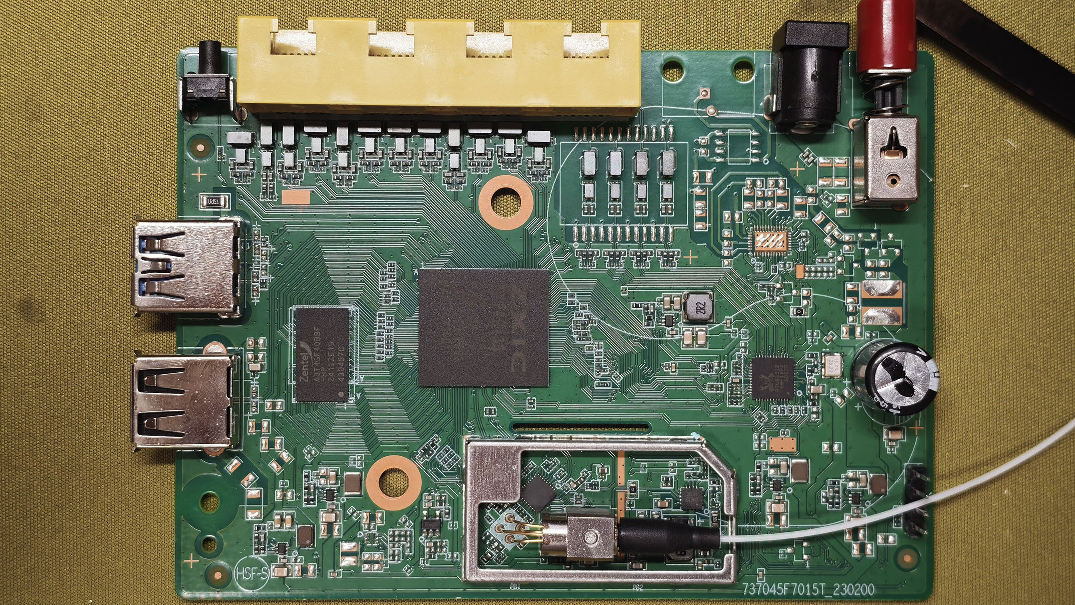 中国移动 F7005MV3 主板正面全景:中间是 ZXIC ZX279133 主控,左侧是 Zentel DDR3 内存,右下方是 Realtek RTL8221B 2.5G PHY,光模块被金属罩覆盖,上方是四个网口,左侧是两个 USB-A